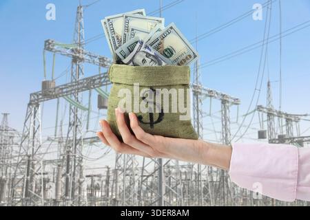 Sparen Sie Geld an Energie. Frau hält Tasche mit Dollar gegen elektrische Umspannwerke draußen, Nahaufnahme Stockfoto