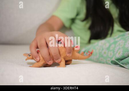 Kind spielt mit Dinosaurierspielzeug auf einer Couch im Wohnzimmer Stockfoto
