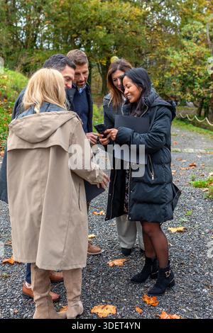 Glückliches, vielfältiges Business-Team, das eine Outdoor-Smartphone-Pause in einer natürlichen Umgebung macht Stockfoto
