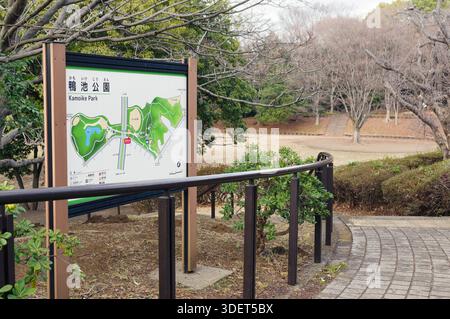 Ein Schild mit einer Karte von Kamoike Park in Yokohama, Kanagawa, Japan. Das Parklayout wird neben einem Pfad angezeigt, mit Bäumen im Hintergrund auf einem W Stockfoto