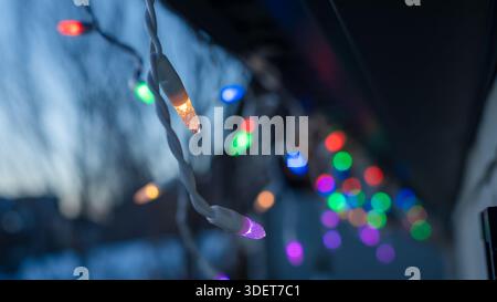 Bunte Lichterketten beleuchten die Abenddämmerung und schaffen ein warmes und einladendes Ambiente, perfekt für Festlichkeiten und Festlichkeiten im Freien Stockfoto