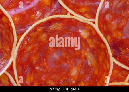 Makroökonomische kulinarische Chorizo-Textur, die abstrakte Esskunst bildet, überlappende ausgehärtete Ringe erzeugen rhythmische Marmorierungen und glänzende Highlights für Editorial und cre Stockfoto