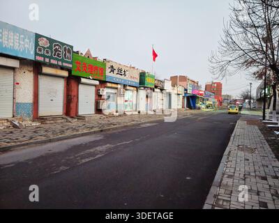 Shutter Shops säumen eine leere Handelsstraße in China Stockfoto