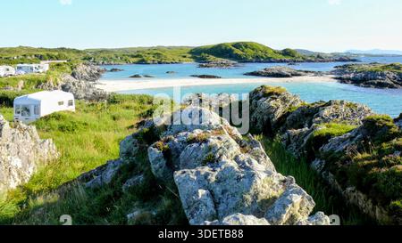 Ein atemberaubender Blick auf den Strand Achmelvich, wo weißer Sand auf türkisfarbenes Atlantikwasser trifft, eingerahmt von felsigen Küsten und üppigem grünem Gras im äußersten Nordwesten Schottlands Stockfoto