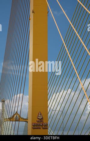Aus nächster Nähe sehen Sie einen Turm und Kabelstege auf der Thotsamarachan-Brücke in Bangkok, von der angrenzenden Rama IX-Brücke mit Monsunwolken dahinter Stockfoto