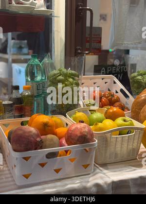Verschiedene frische Früchte einschließlich Persimmons und Trauben, die in Kisten in einem römischen Lebensmittelgeschäft oder einem Lebensmittelgeschäft angeordnet werden. Stockfoto