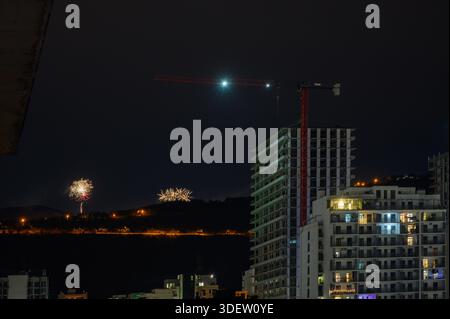 Dynamisches Feuerwerk erleuchtet den Nachthimmel über Saburtalo, Tiflis, während Neujahrsfeiern. Rote, grüne und goldene Lichteffekte stehen im Kontrast zu Stockfoto