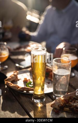 Die Leute genießen Bier und Pizza draußen im Abendlicht Stockfoto