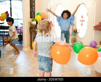 Kinder feiern drinnen mit Ballons und fröhlicher Energie. Stockfoto