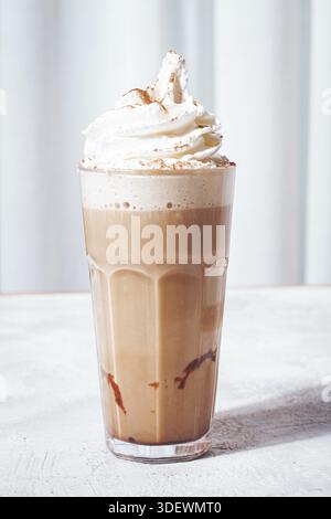 Cremiger Eiskaffee, garniert mit Schlagsahne und Zimt, serviert in einem klaren Glas Stockfoto