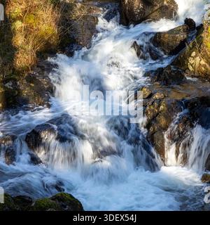 Nahaufnahme eines schnell fließenden Wasserfalls, der über Felsen plätschert Stockfoto