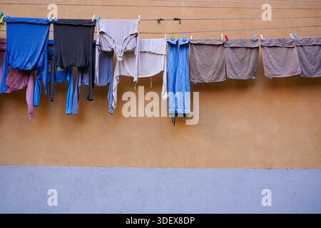 Wäschereiservice hängt an Wäscheleinen über einer ruhigen Straße. Das tägliche Leben in Venedig, Venetien, Italien. Stockfoto