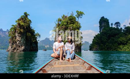 Das Paar genießt einen ruhigen Moment auf einem Holzboot, umgeben von atemberaubenden Kalksteinformationen und üppigem Grün am Cheow Lan Lake, Khao Sok, Thailand, und schafft unvergessliche Erinnerungen. || Modell freigegeben Stockfoto