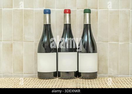Eine Sammlung von Flaschen aus verschiedenen Weingütern, voll und mit lesbaren Etiketten, die in horizontaler Linie an einer Wand als dekoratives Aufbewahrungselement angebracht werden. Stockfoto