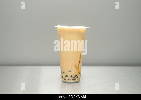 Ein gesalzener Karamell-Bubble-Tee mit gerösteter beiger Farbe und dicken Fäden von Karamell-Sauce, die sich an der Innenseite des Glases anschmiegen Stockfoto