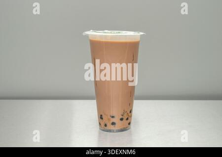 Ein dunkler Schokoladen-Bubble-Tee mit einem großzügigen Topping Schlagsahne und bestreuten Schokoladenspänen, neben dem Deckel, wo ein Loch für t geschnitten wurde Stockfoto