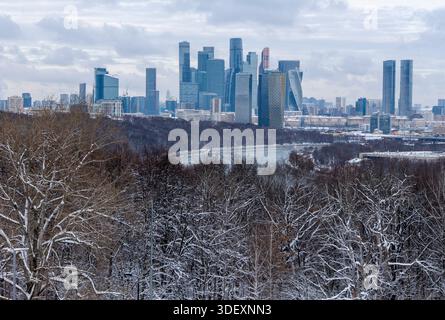 Ein atemberaubender Blick auf eine winterliche Stadtlandschaft mit eleganten Wolkenkratzern vor der Kulisse eines schneebedeckten Waldes und eines Flusses unter dramatischen bewölkten en s Stockfoto