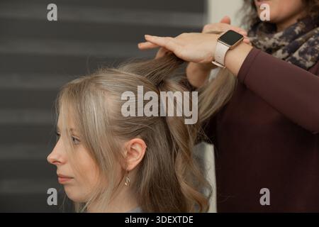 Nahaufnahme eines Friseurs, der einen Pferdeschwanz während einer professionellen Friseursession in einem Schönheitssalon fixiert. Konzept von Pflege-, Pflege- und Friseurpflege Stockfoto