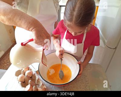 Eine Großmutter und ihre Enkelin machen Pfannkuchen in der Küche Stockfoto