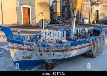 Traditionelles sizilianisches Fischerboot („Gozzo“), das als Denkmal auf einem Stadtplatz ausgestellt wird. Stockfoto
