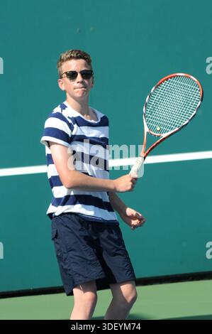 Junger Mann, der auf einem Tennisplatz im Freien Tennis spielt, während eines Trainings lässige Sportkleidung trägt. Stockfoto