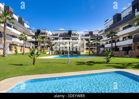 Moderne Wohngebäude mit mehreren Pools, Palmen und grünen Grünflächen Stockfoto