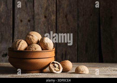 Walnüsse in Holzschale auf rustikalem hölzernem Hintergrund Stockfoto