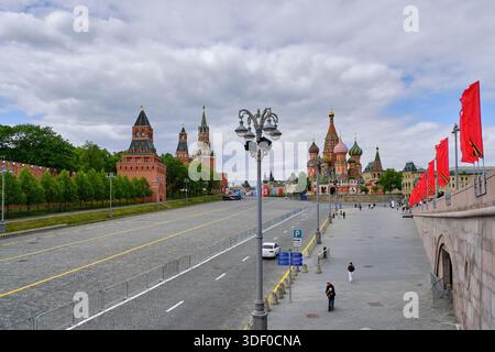 Großer Blick auf den Roten Platz mit den Mauern des Kreml, die Basilius Kathedrale und die festlichen roten Fahnen entlang der Promenade Stockfoto