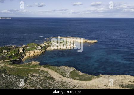 Aus der Vogelperspektive auf türkisfarbenes Wasser, das die zerklüftete Küste und die antiken Ruinen von Plemmirio, Sizilien, Italien umgibt. Stockfoto