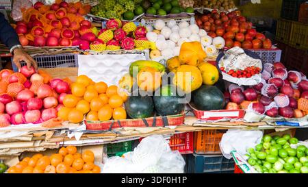Reichlich bestückter Marktstand mit verschiedenen Früchten wie Äpfeln, Melonen und Zitrusfrüchten, die Frische und lebendige natürliche Farben bieten. Stockfoto