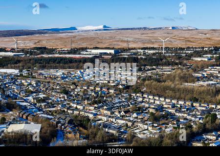 Verschneite Häuser in Ebbw Vale mit Windturbinen und Bergen im Hintergrund Stockfoto
