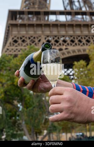 Ausgießen und Trinken von französischem Sekt aus Tulpenglas mit Blick auf die Straßen, Gebäude und Türme von Paris, Hochzeitsveranstaltung in Paris Stockfoto