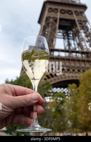 Ausgießen und Trinken von französischem Sekt aus Tulpenglas mit Blick auf die Straßen, Gebäude und Türme von Paris, Hochzeitsveranstaltung in Paris Stockfoto