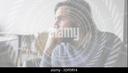 Sitzender bärtiger Mann mit grauem Pullover, aufliegendes Kinn auf der Hand im Sessel, Spiralüberzug Stockfoto