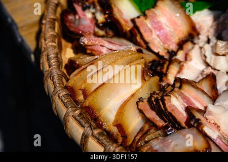 Geschnittenes, geräuchertes Schweinefleisch in Miao Bambustablett Stockfoto