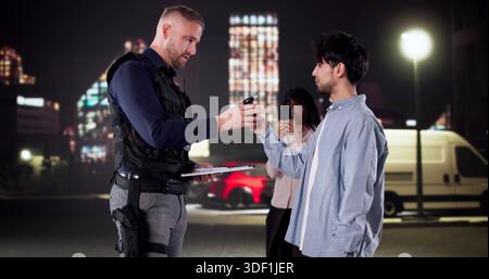 Der Polizeibeamte Führt Einen Atemtest Während Des Verkehrs Durch; Filme Von Umstehenden. Stockfoto