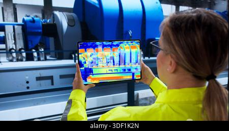 Weibliche Ingenieurin Inspiziert Gasturbine Im Kraftwerk Mit Wärmebildkamera. Stockfoto