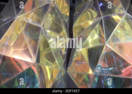 Abstrakter geometrischer Hintergrund mit irisierenden Prismenfacetten, die goldenes Licht reflektieren, mit lebendigen Farben, die ein modernes und futuristisches Gefühl schaffen Stockfoto