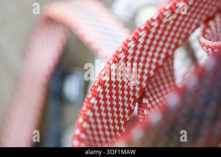 Nahaufnahme eines rot-weißen gewebten Kunststoffbands oder Griffs mit verschwommenem Hintergrund, das ein Strukturmuster und handwerkliche Handwerkskunst zeigt Stockfoto