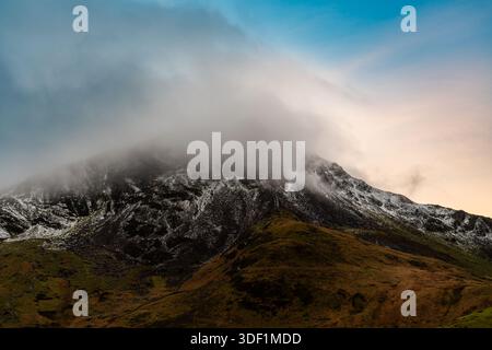 Schneebedeckte Snowdonia-Berghänge im Winter unter starker Wolke Stockfoto