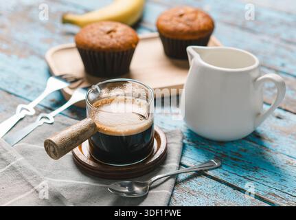 Eine Tasse heißer schwarzer Kaffee, Espresso, frisch gebackene Muffins. Bananen-Cupcake-Nahaufnahme als Dessert für die Kaffeepause. Draufsicht. Erfrischend am Morgen und am Tag Stockfoto