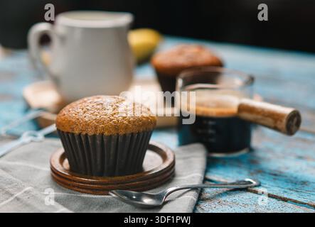 Eine Tasse heißer schwarzer Kaffee, Espresso, frisch gebackene Muffins. Bananen-Cupcake-Nahaufnahme als Dessert für die Kaffeepause. Draufsicht. Erfrischend am Morgen und am Tag Stockfoto