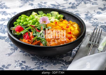 Köstliche Lachs- und Avocado-Poke-Schüssel garniert mit Sesamsamen und Algen, stilisierte Lebensmittelfotografie, lebendige Farbkomposition. Stockfoto