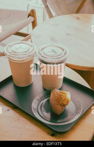 Zwei Kaffees zum Mitnehmen und ein Muffin auf einem Holztisch Stockfoto