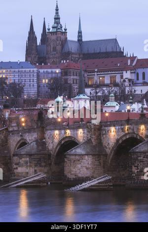 Blick auf die berühmte Karlsbrücke mit ihren verwitterten Steinbögen, die sich im ruhigen Wasser spiegeln, führt zur majestätischen Prager Burg, Prag, Pr Stockfoto