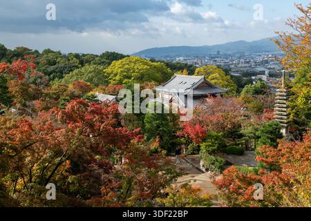 Blick auf das lebhafte Herbstlaub rund um traditionelle Tempel und Pagoden, im Kontrast zur fernen modernen Stadtlandschaft, Kyoto, Kyoto, Japan. Stockfoto