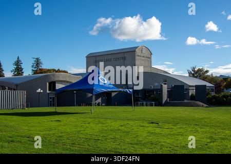 Ein großes blaues Zelt auf einem grünen Rasen vor dem Great Lake Centre, ein modernes Gebäude mit geschwungenem Dach und klarem blauem Himmel im Hintergrund. Stockfoto