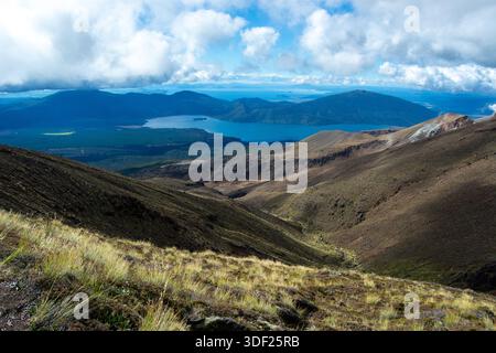 Ein atemberaubender Blick auf eine bergige Landschaft mit sanften Hügeln, einem ruhigen See und einem dramatischen Himmel voller Wolken. Der Vordergrund zeigt Stockfoto