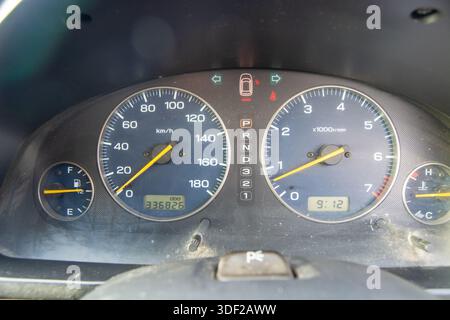 Nahansicht des Armaturenbretts eines Fahrzeugs mit Tachometer, Drehzahlmesser, Kraftstoffanzeige und Kilometerzähler. Das Armaturenbrett ist leicht staubig, was auf u hinweist Stockfoto