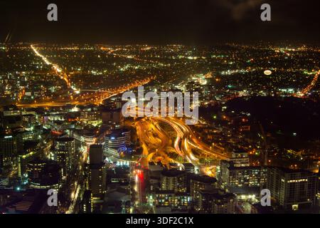 Aus der Vogelperspektive sehen Sie eine lebhafte Stadtlandschaft bei Nacht mit beleuchteten Gebäuden, belebten Autobahnen und einer weitläufigen Stadtlandschaft voller Lichter. Stockfoto